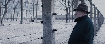 Movie still from “Denial” (2016), directed by Mick Jackson – A pole with barbed wire around it in a field; Close Up shot, Over the shoulder angle