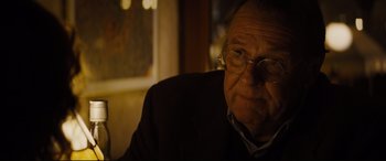 Movie still from “Denial” (2016), directed by Mick Jackson – An older man wearing glasses sitting in front of a window; Close Up shot, Over the shoulder angle