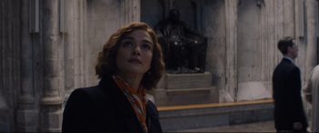 Movie still from “Denial” (2016), directed by Mick Jackson – A woman standing in front of a statue of a person; Medium shot, Low angle