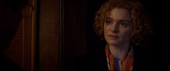 Movie still from “Denial” (2016), directed by Mick Jackson – A woman with a scarf around her neck looks at the camera; Close Up shot, Over the shoulder angle