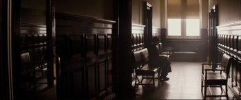 Movie still from “Denial” (2016), directed by Mick Jackson – A person sitting on a bench in a room; Extreme Wide shot, High angle