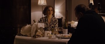 Movie still from “Denial” (2016), directed by Mick Jackson – A woman sitting at a table with a glass of wine; Medium shot, Over the shoulder angle