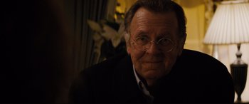 Movie still from “Denial” (2016), directed by Mick Jackson – An older man wearing glasses and a suit; Close Up shot, Over the shoulder angle