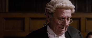 Movie still from “Denial” (2016), directed by Mick Jackson – An old man wearing a wig and glasses; Close Up shot, Low angle