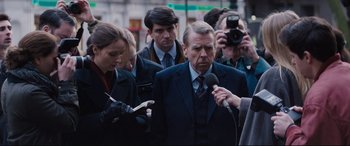 Movie still from “Denial” (2016), directed by Mick Jackson – A group of people standing next to each other on the street; Medium shot, Over the shoulder angle
