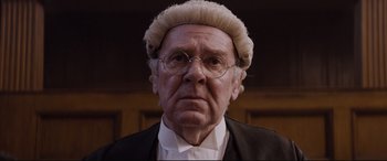 Movie still from “Denial” (2016), directed by Mick Jackson – An old man wearing a judge's wig and glasses; Close Up shot, Low angle