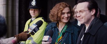 Movie still from “Denial” (2016), directed by Mick Jackson – A woman smiles while being interviewed by a police officer; Medium shot, Over the shoulder angle