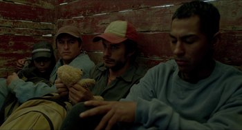 Movie still from “Desierto” (2015), directed by Jonás Cuarón – A group of men sitting next to each other holding food; Medium shot, High angle