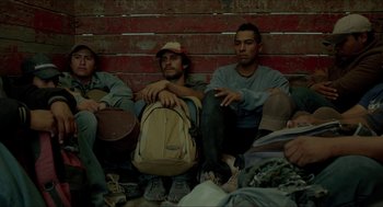 Movie still from “Desierto” (2015), directed by Jonás Cuarón – A group of men sitting next to each other on the ground; Medium shot, Low angle