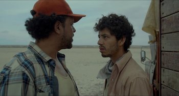 Movie still from “Desierto” (2015), directed by Jonás Cuarón – Two men standing next to each other on a beach; Close Up shot, Over the shoulder angle