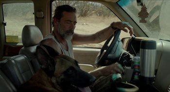 Movie still from “Desierto” (2015), directed by Jonás Cuarón – A man driving a car with a dog in the driver's seat; Close Up shot, Over the shoulder angle