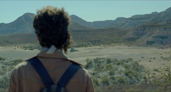 Movie still from “Desierto” (2015), directed by Jonás Cuarón – A man standing on top of a dirt field; Wide shot, Over the shoulder angle