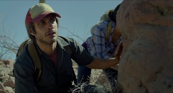 Movie still from “Desierto” (2015), directed by Jonás Cuarón – A man and a woman in a field near a rock; Close Up shot, Low angle