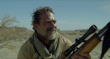 Movie still from “Desierto” (2015), directed by Jonás Cuarón – A man holding a rifle in a desert area; Close Up shot, Over the shoulder angle