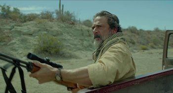 Movie still from “Desierto” (2015), directed by Jonás Cuarón – A man with a beard is holding a gun in his hand; Close Up shot, Over the shoulder angle