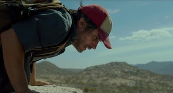 Movie still from “Desierto” (2015), directed by Jonás Cuarón – A man with a backpack and a hat climbing up a rock; Close Up shot, Low angle