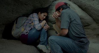 Movie still from “Desierto” (2015), directed by Jonás Cuarón – A man and a woman sitting on the ground; Medium shot, Overhead angle