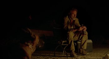 Movie still from “Desierto” (2015), directed by Jonás Cuarón – A man sitting on a chair next to a dog; Medium shot, Over the shoulder angle