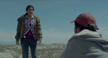 Movie still from “Desierto” (2015), directed by Jonás Cuarón – A young woman standing next to a man in a field; Medium shot, Over the shoulder angle