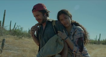 Movie still from “Desierto” (2015), directed by Jonás Cuarón – A man and a woman in a field with a backpack; Close Up shot, Low angle