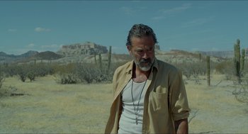Movie still from “Desierto” (2015), directed by Jonás Cuarón – An older man with a beard wearing a white t - shirt; Medium shot, Over the shoulder angle