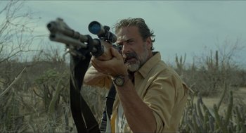 Movie still from “Desierto” (2015), directed by Jonás Cuarón – A man is holding a rifle in a field; Close Up shot, Over the shoulder angle