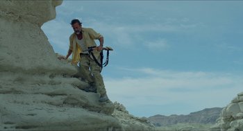 Movie still from “Desierto” (2015), directed by Jonás Cuarón – A man with a camera climbing up a mountain; Wide shot, Low angle