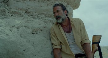 Movie still from “Desierto” (2015), directed by Jonás Cuarón – A man sitting on a rock near a rock wall; Close Up shot, Low angle