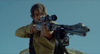 Movie still from “Desierto” (2015), directed by Jonás Cuarón – A man is holding a rifle and aiming at something; Medium shot, Low angle