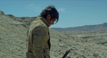 Movie still from “Desierto” (2015), directed by Jonás Cuarón – A man in a brown jacket looking down at a piece of paper; Medium shot, Over the shoulder angle