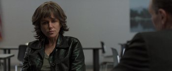 Movie still from “Destroyer” (2018), directed by Karyn Kusama – A woman sitting in front of a table in front of a wall; Close Up shot, Over the shoulder angle