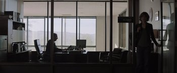 Movie still from “Destroyer” (2018), directed by Karyn Kusama – A man sitting at a desk in front of a window; Wide shot, Low angle