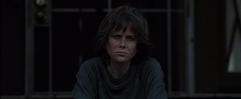 Movie still from “Destroyer” (2018), directed by Karyn Kusama – A woman sitting in front of a building looking at the camera; Close Up shot, Low angle