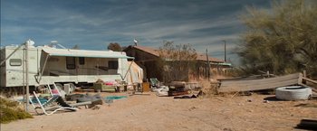 Movie still from “Destroyer” (2018), directed by Karyn Kusama – An rv is parked in the middle of a dirt field; Extreme Wide shot, Low angle