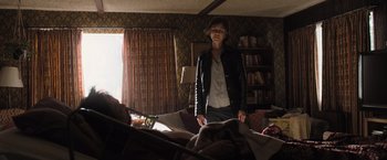 Movie still from “Destroyer” (2018), directed by Karyn Kusama – A woman standing in front of a bed in a living room; Wide shot, Over the shoulder angle