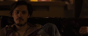 Movie still from “Destroyer” (2018), directed by Karyn Kusama – A person sitting on a couch in a dark room; Close Up shot, Over the shoulder angle