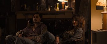 Movie still from “Destroyer” (2018), directed by Karyn Kusama – A man and a woman sitting on a couch in a living room; Medium shot, Low angle