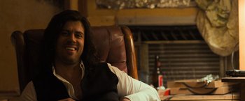 Movie still from “Destroyer” (2018), directed by Karyn Kusama – A man sitting in a leather chair in front of a fire place; Close Up shot, Over the shoulder angle