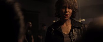Movie still from “Destroyer” (2018), directed by Karyn Kusama – A woman in a leather jacket is standing in a dark room; Close Up shot, Over the shoulder angle