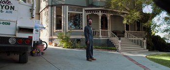 Movie still from “Destroyer” (2018), directed by Karyn Kusama – A man standing in front of an old house; Wide shot, Low angle