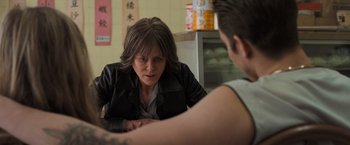 Movie still from “Destroyer” (2018), directed by Karyn Kusama – A woman sitting in front of a man in front of a counter; Close Up shot, Over the shoulder angle