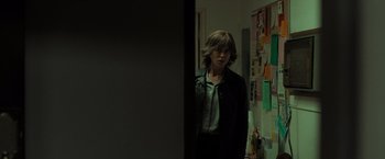 Movie still from “Destroyer” (2018), directed by Karyn Kusama – A person standing in a room with a bunch of post - its on the wall behind them; Medium shot, Over the shoulder angle