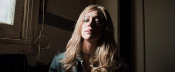 Movie still from “Destroyer” (2018), directed by Karyn Kusama – A woman with long blonde hair wearing glasses; Close Up shot, Low angle