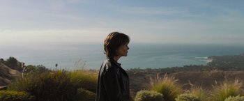 Movie still from “Destroyer” (2018), directed by Karyn Kusama – A woman standing on top of a grass covered hill; Medium shot, Over the shoulder angle