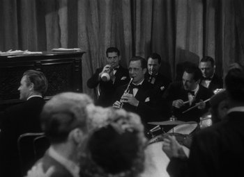 Movie still from “Detour” (1945), directed by Edgar G. Ulmer – A black and white photo of a group of men playing instruments; Medium shot, High angle