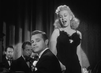 Movie still from “Detour” (1945), directed by Edgar G. Ulmer – A man and a woman singing in front of an audience; Medium shot, Low angle