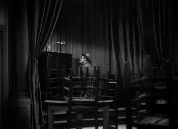 Movie still from “Detour” (1945), directed by Edgar G. Ulmer – A man sitting at a table in front of an organ; Wide shot, High angle