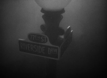 Movie still from “Detour” (1945), directed by Edgar G. Ulmer – A street sign on a street light in the dark; Extreme Wide shot, High angle