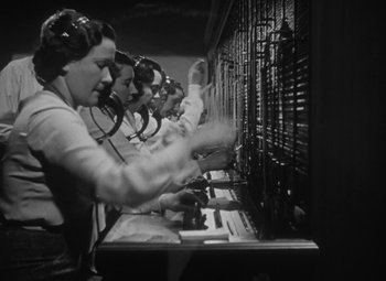 Movie still from “Detour” (1945), directed by Edgar G. Ulmer – A black and white photo of a group of women working at a telephone switchboard; Medium shot, Low angle