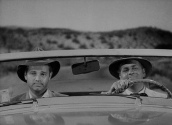 Movie still from “Detour” (1945), directed by Edgar G. Ulmer – A couple of men in hats in the back of a car; Medium shot, Low angle